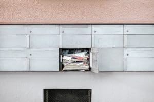 A mail box overflows with newspapers, letters, and more, likely because mail forwarding or address changes weren't set up before moving in Ottawa.