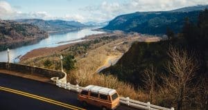 A van sits parked on the side of a road looking over a beautiful river valley, possibly with a driver trying to find something they forgot at the start of their long-distance move.