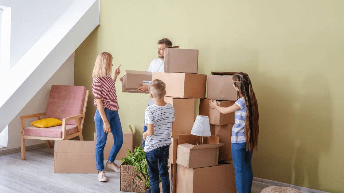 A family packing their belongings for a move, with insurance coverage in the background