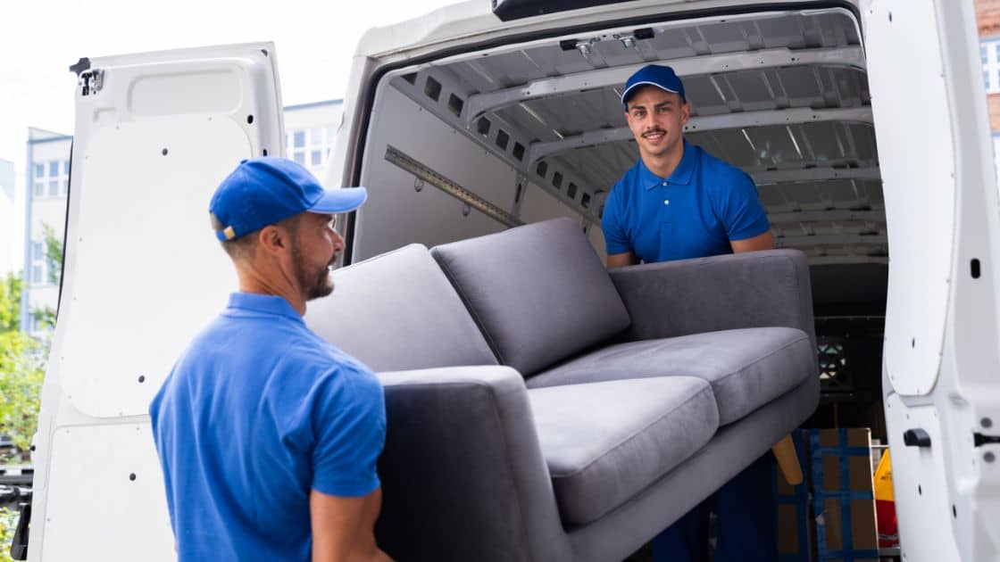 Movers carrying a couch into a new location.